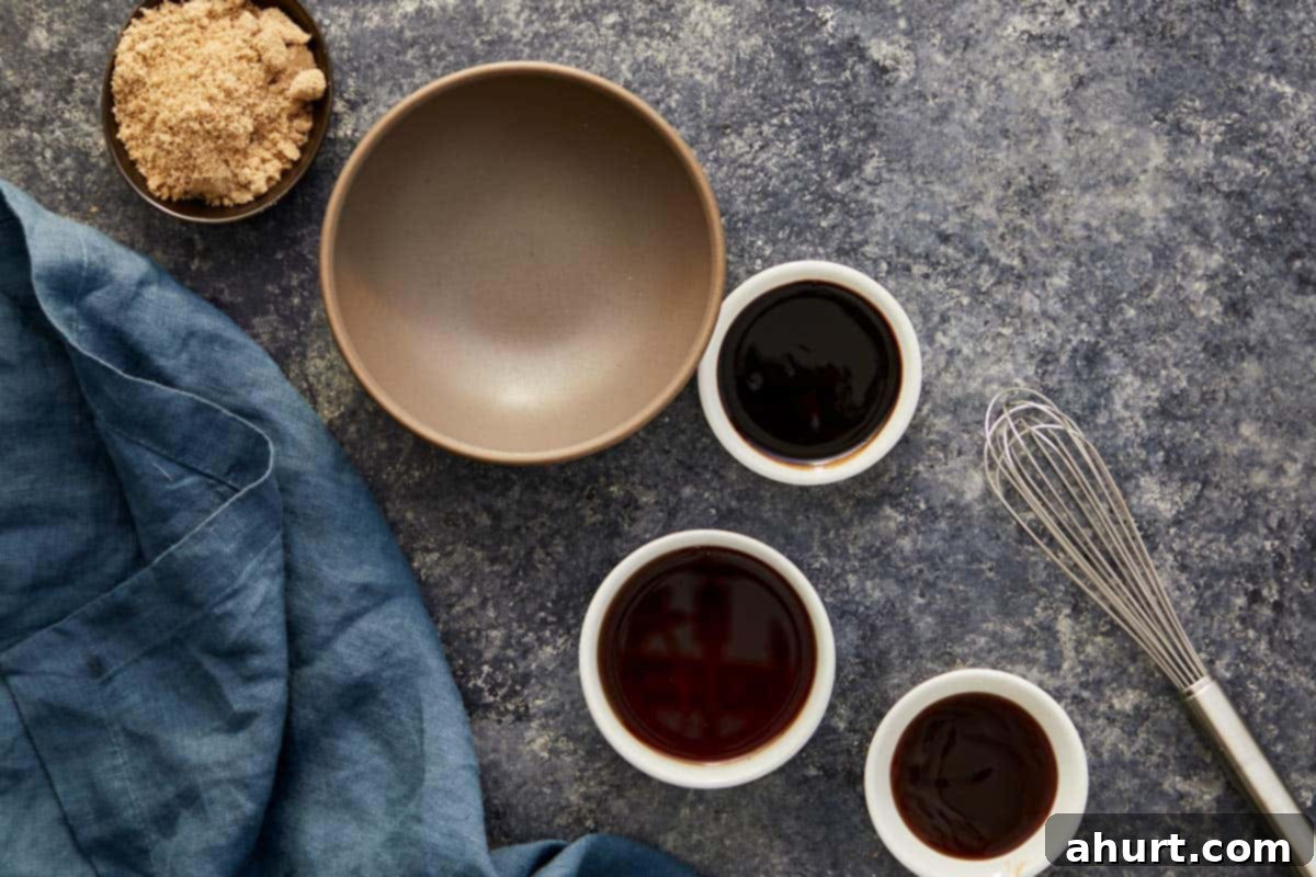 Small prep bowls containing the individual components for Pad Thai sauce: tamarind puree, fish sauce, oyster sauce, and brown sugar, arranged around a whisk.