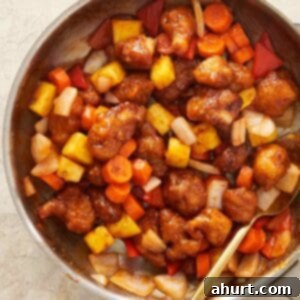 Homemade sweet and sour chicken with crispy bites of chicken, fresh vegetables, pineapple, and a glossy tangy sauce.