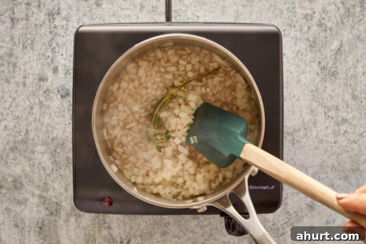 Simmering chopped onions with thyme and white wine in a saucepan to create a fragrant base.