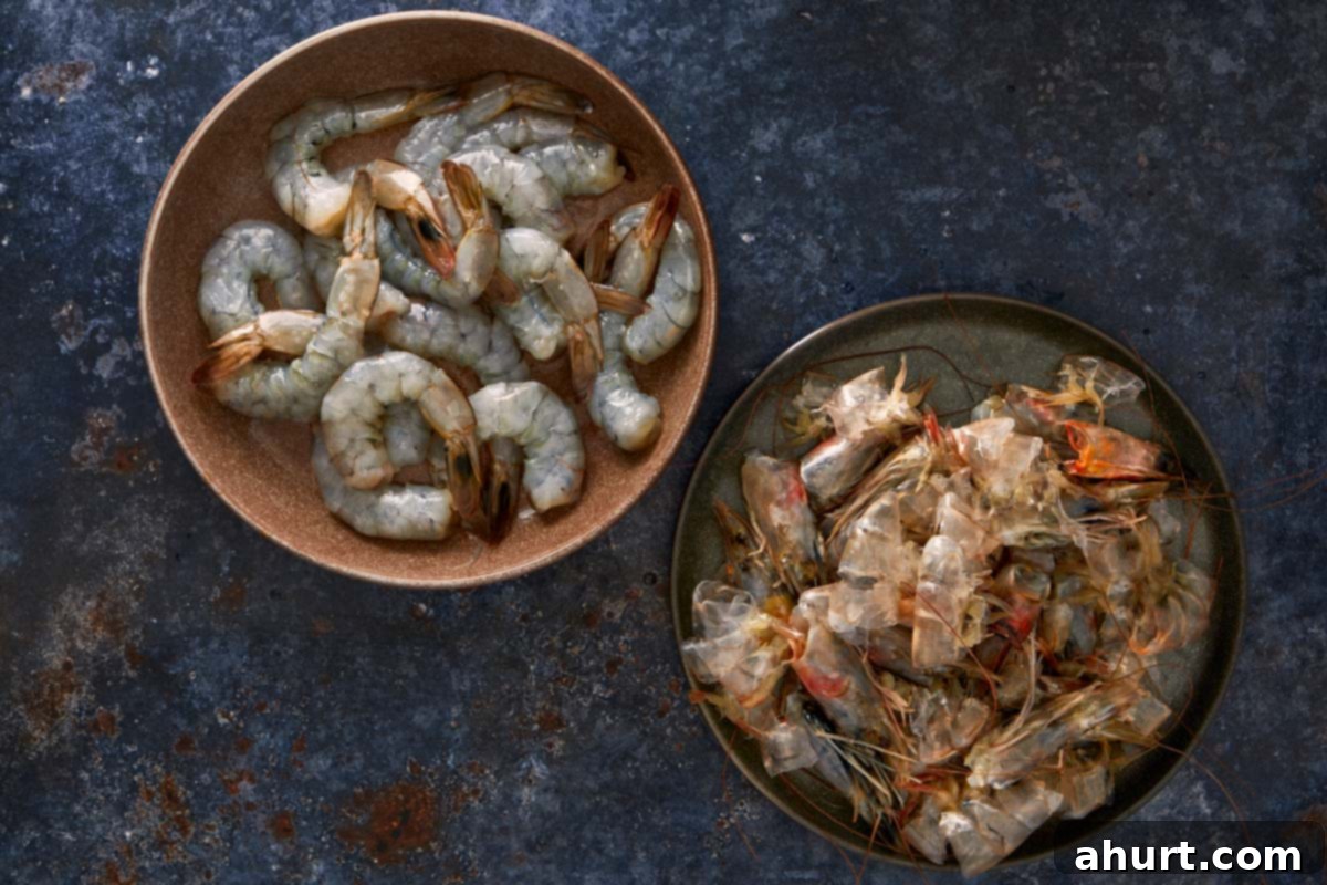 Peeled raw shrimp in one bowl and shrimp shells and heads in another, ready to make broth.