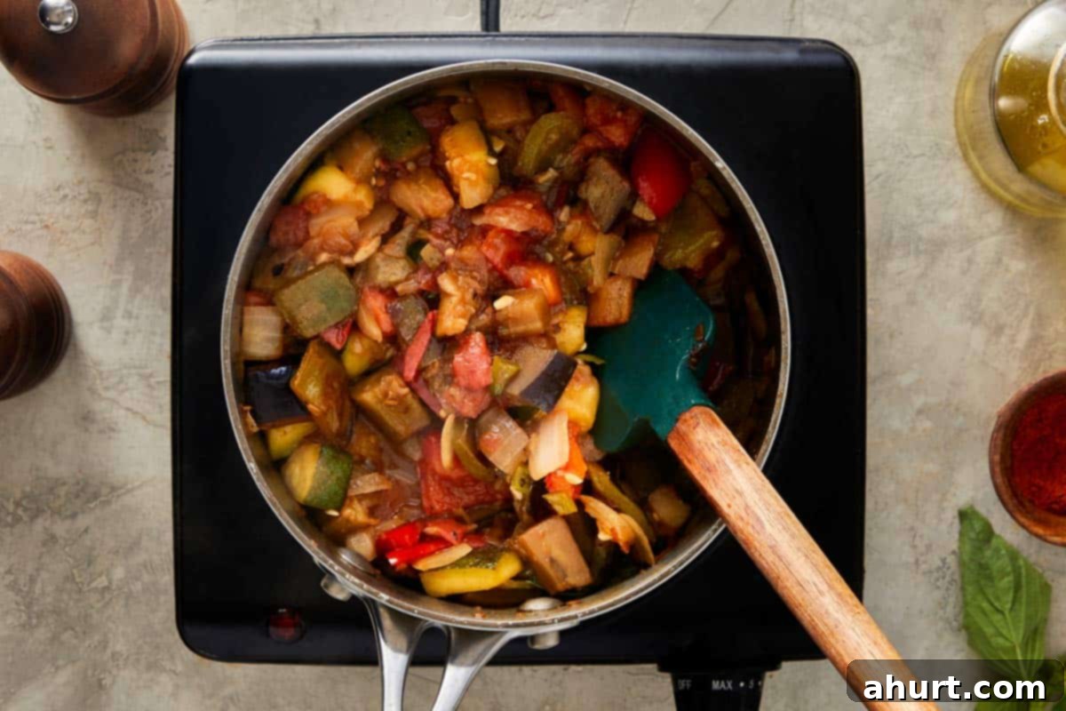 Cooked ratatouille being stirred in a pot.