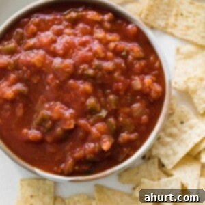 A bowl of vibrant homemade salsa, featuring fresh tomatoes, onions, garlic, Serrano peppers, jalapeños, cumin and oregano.
