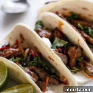 Korean Bulgogi BBQ Beef Tacos with tender marinated beef, garnished with sesame seeds and lemon wedges