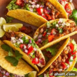 Beef tacos with guacamole, salsa, and lime wedges on a plate, ready to serve.