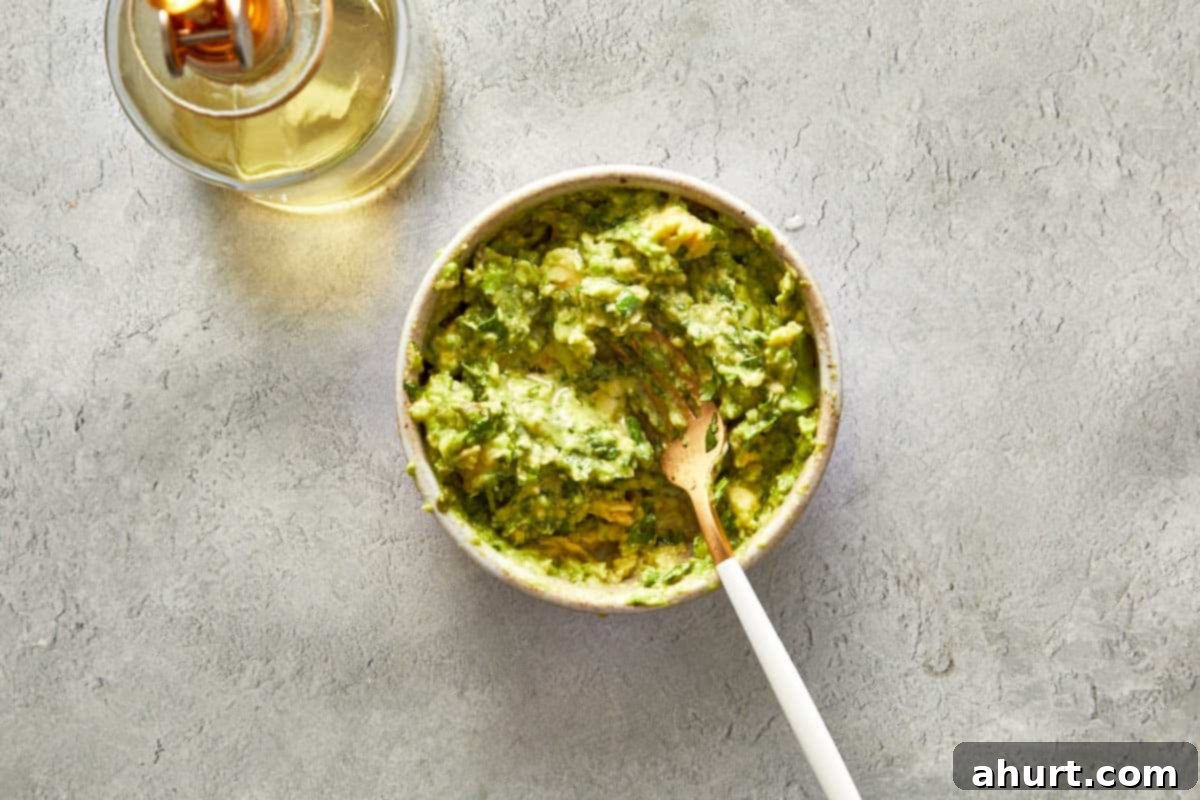Bowl of fresh, vibrant green guacamole with a spoon, ready to be served or chilled.