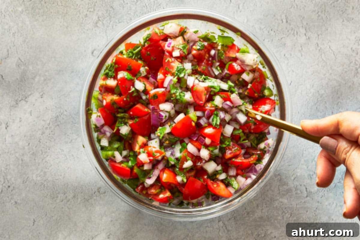 A vibrant bowl of freshly prepared pico de gallo, featuring chopped tomatoes, red onion, and cilantro, glistening with lime juice.