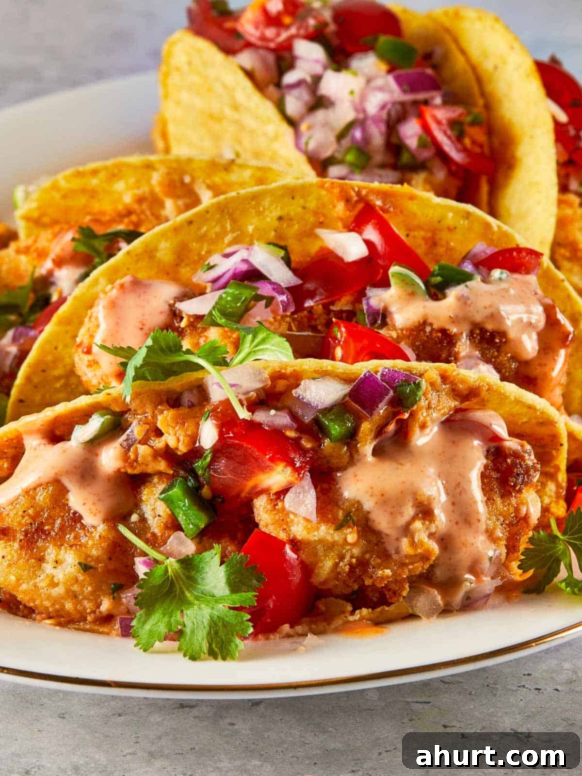 Golden Crispy Fish Tacos 2 Close-up of crispy fish tacos topped with pico de gallo, cilantro, and spicy mayo