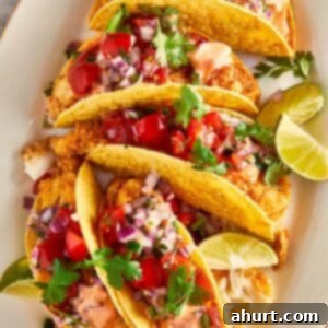 Golden Crispy Fish Tacos 11 Crispy fish tacos topped with pico de gallo, cilantro, and lime wedges on a plate