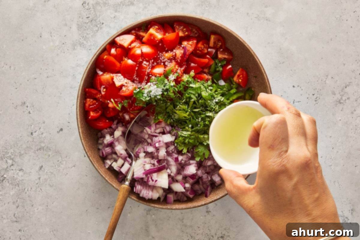 Golden Crispy Fish Tacos 4 Hand pouring lime juice over chopped tomatoes, onions, and cilantro in a bowl