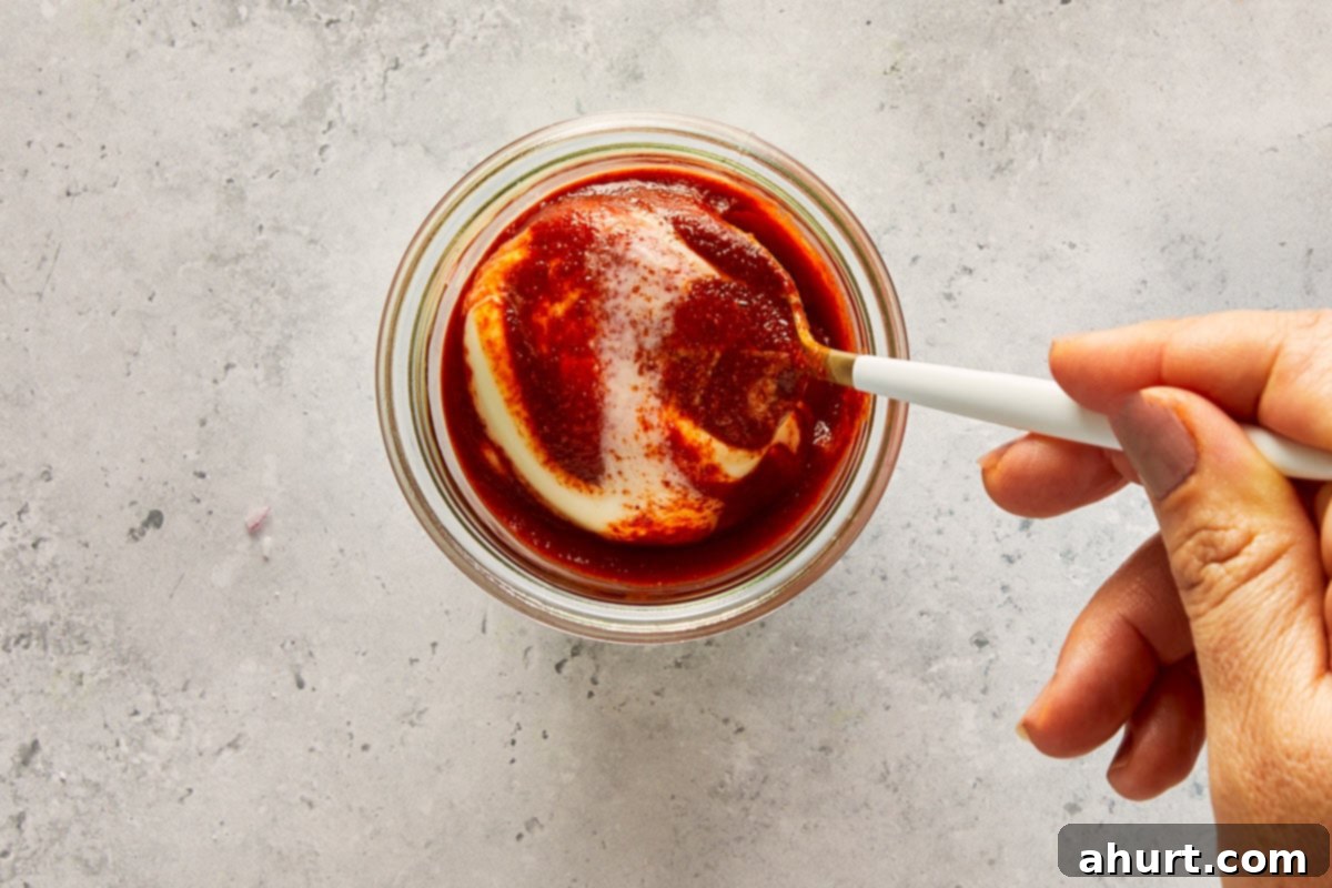 Golden Crispy Fish Tacos 5 Hand mixing mayonnaise with sriracha in a small glass bowl