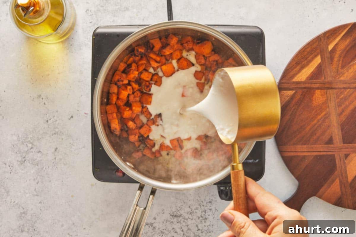 Golden Crispy Fish Tacos 6 Hand pouring coconut cream into a saucepan with cooked sweet potato cubes