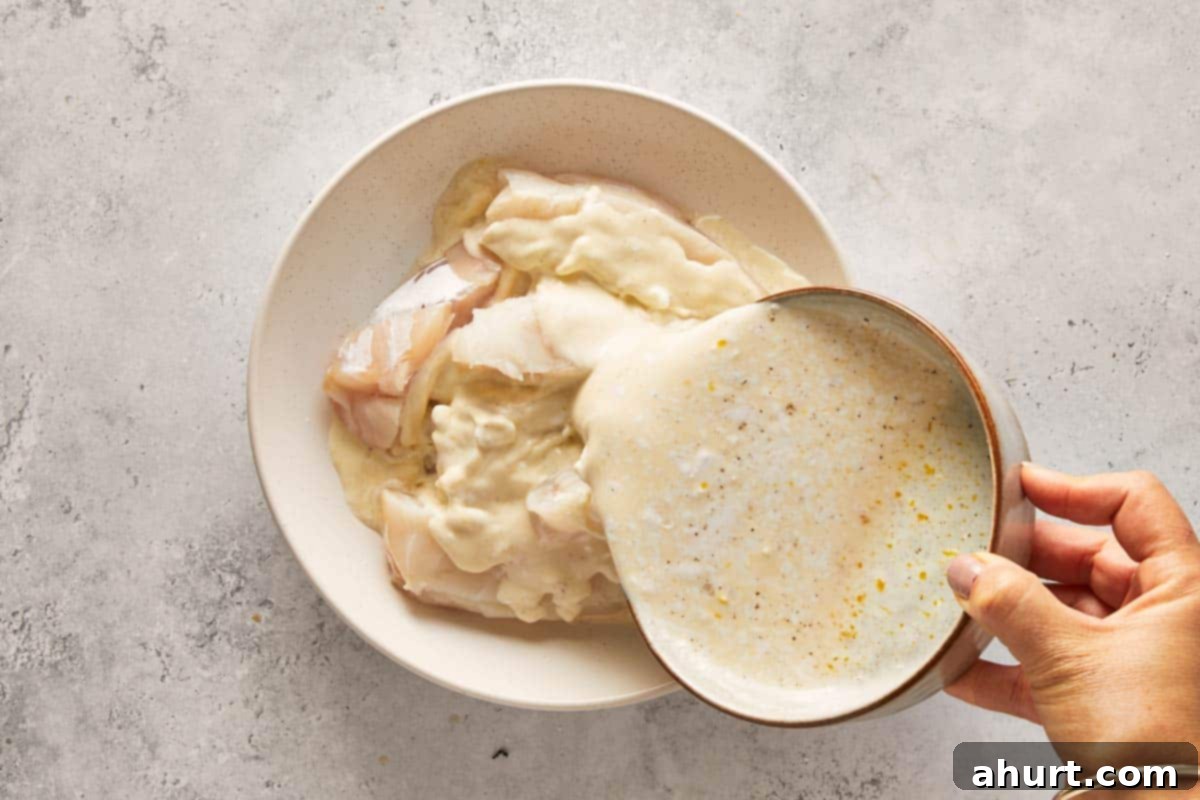 Golden Crispy Fish Tacos 7 Hand pouring marinade over raw fish fillets in a bowl