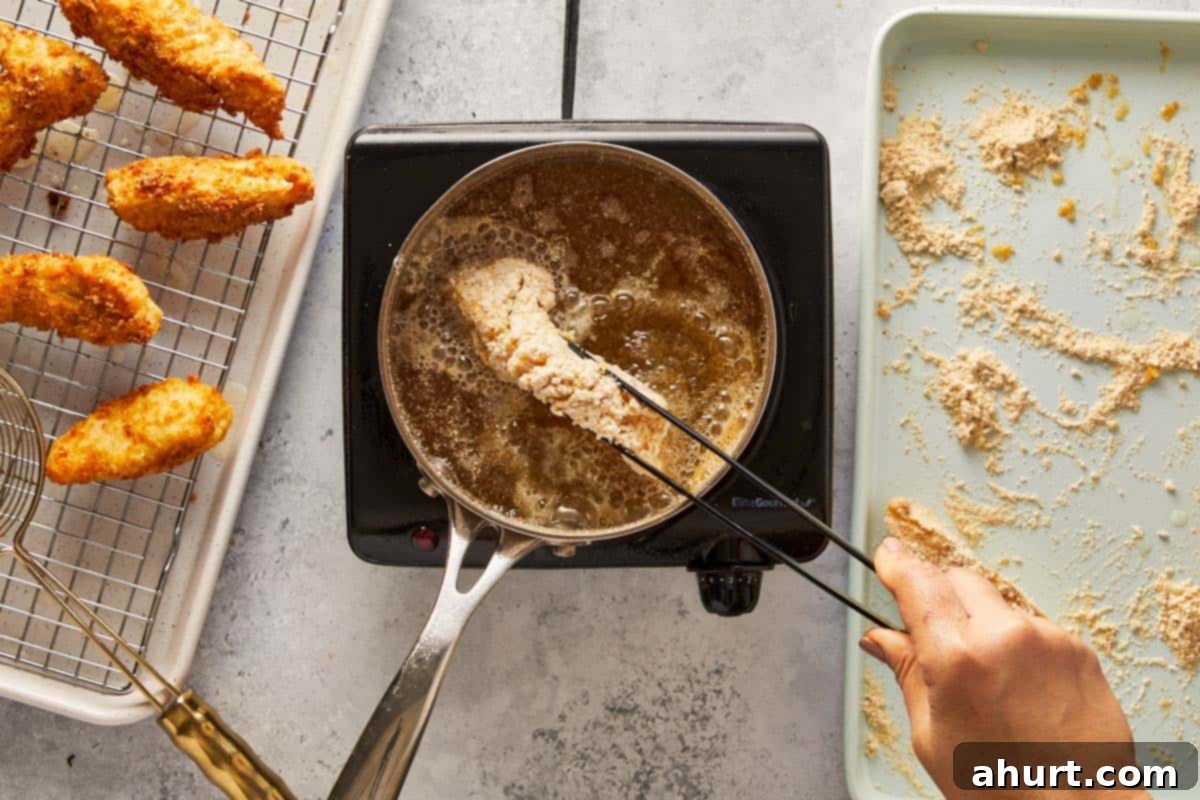 Golden Crispy Fish Tacos 8 Hand frying breaded fish fillet in hot oil with golden pieces draining on a rack