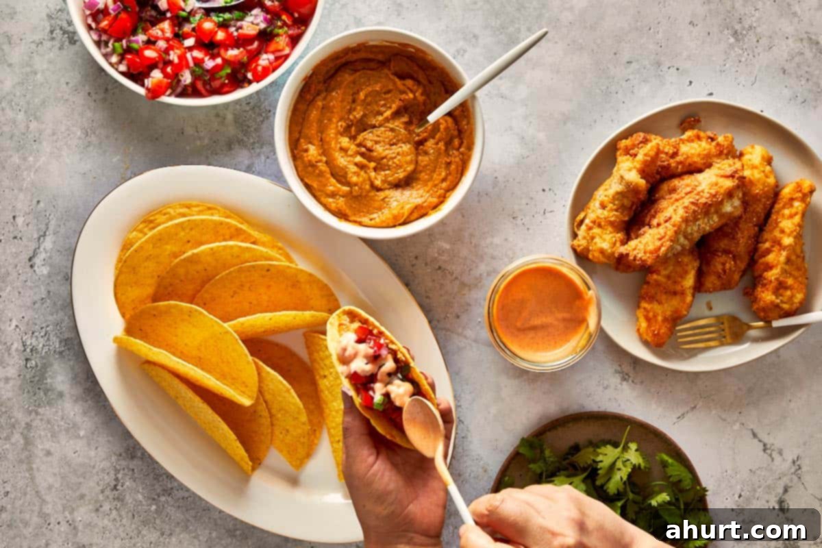 Golden Crispy Fish Tacos 9 Hands assembling crispy fish tacos with pico de gallo, sauce, and taco shells on the table