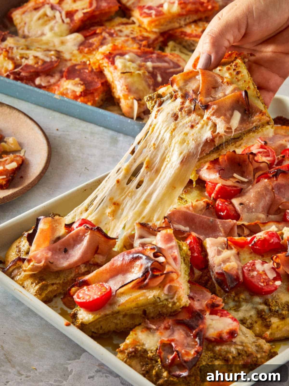 Focaccia-Style Pizza 2 Hand pulling a cheesy slice of focaccia pizza.