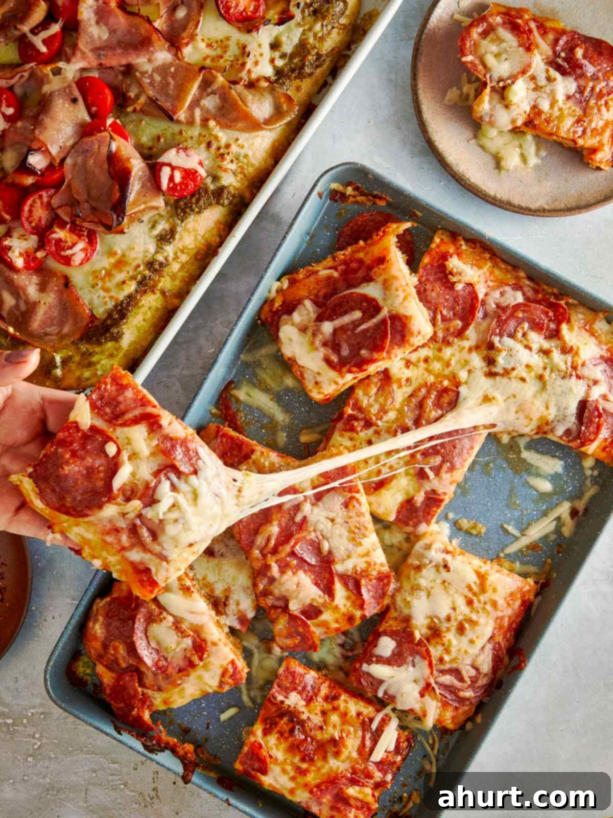 Focaccia-Style Pizza 12 Hand pulling a cheesy slice of focaccia pizza.