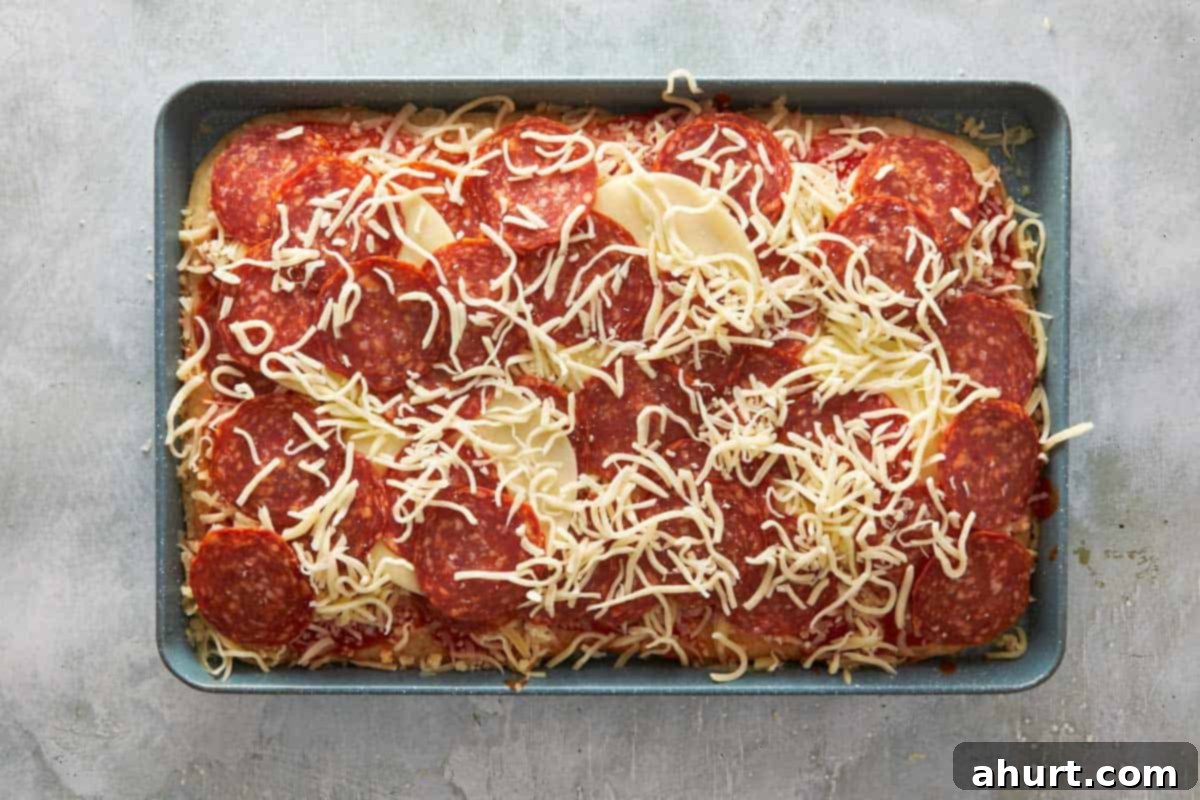 Focaccia-Style Pizza 8 Unbaked pepperoni focaccia pizza topped with tomato sauce, mozzarella, and provolone before baking.