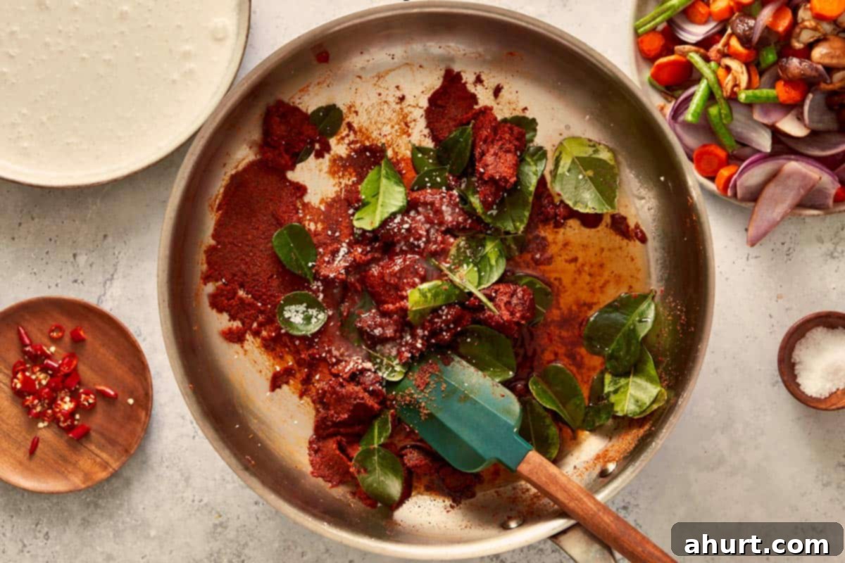 Panang curry paste and kaffir lime leaves sizzling in oil, releasing rich Thai aromas as the curry base starts to come together.
