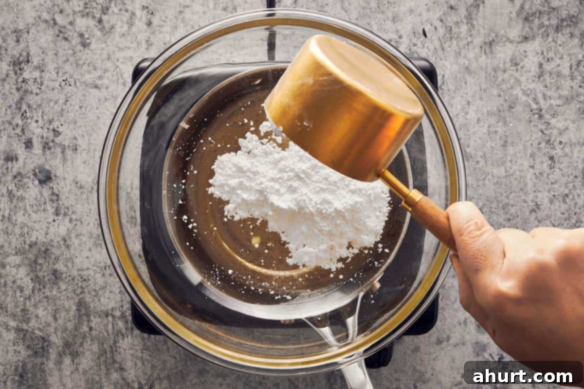 Pouring powdered sugar into a bowl over simmering water to make Swiss meringue.