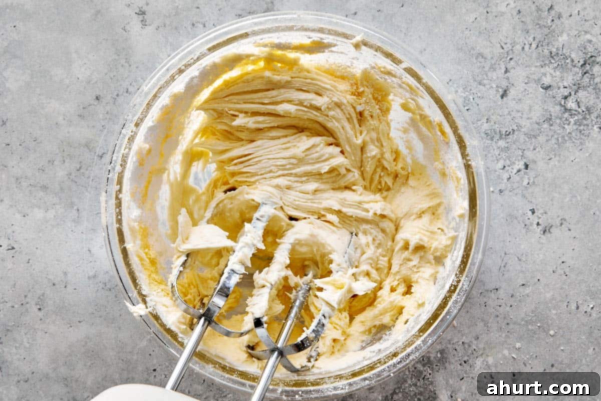 Spooktacular Red Velvet Cake Pops 6 A close-up shot of fluffy vanilla frosting being whipped to perfection in a mixing bowl with an electric mixer. The texture is smooth and airy.
