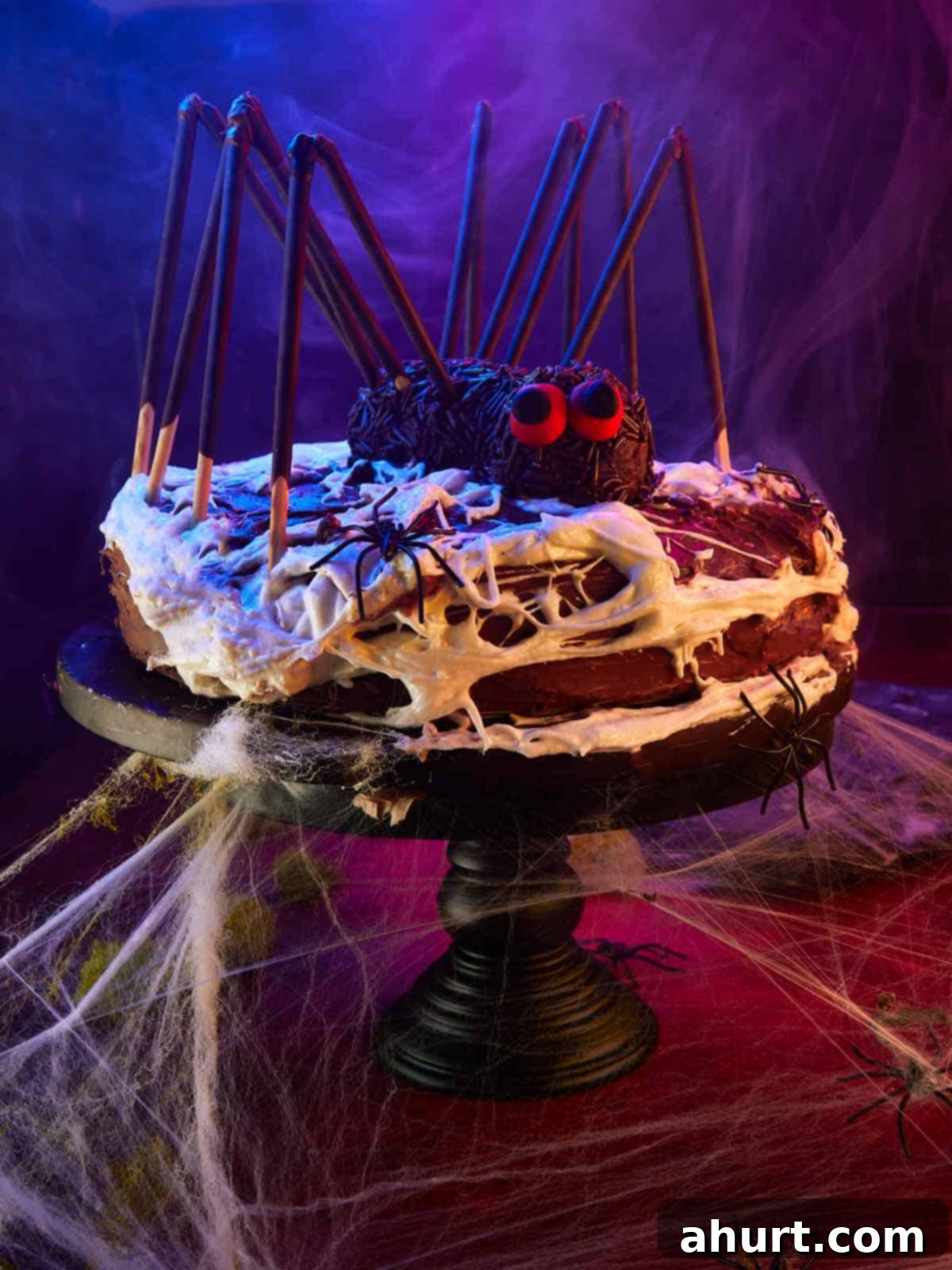 Chocolate Spider Layer Cake on a black cake stand with dramatic lighting, smoke, and glowing purple and blue hues for Halloween.
