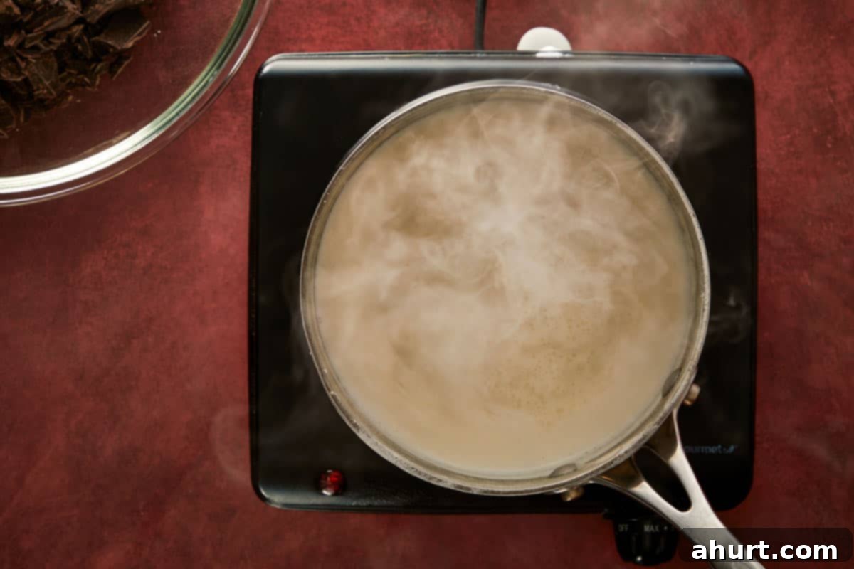Heating cream on the stove until steaming to prepare the chocolate ganache.