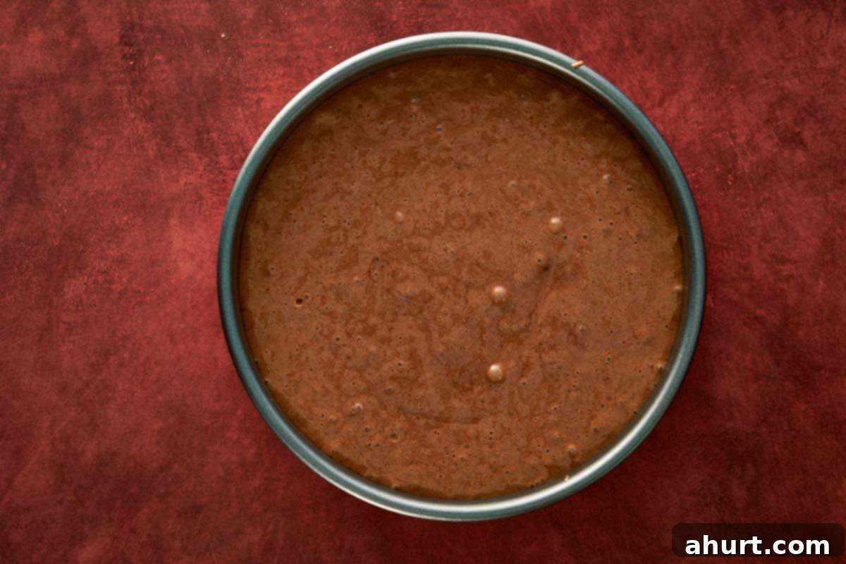 Chocolate chiffon cake batter poured evenly into a round pan, ready for baking.