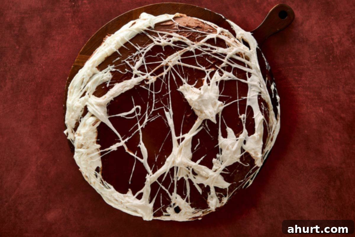 Stretching melted marshmallows over the frosted cake to form spooky web strands.
