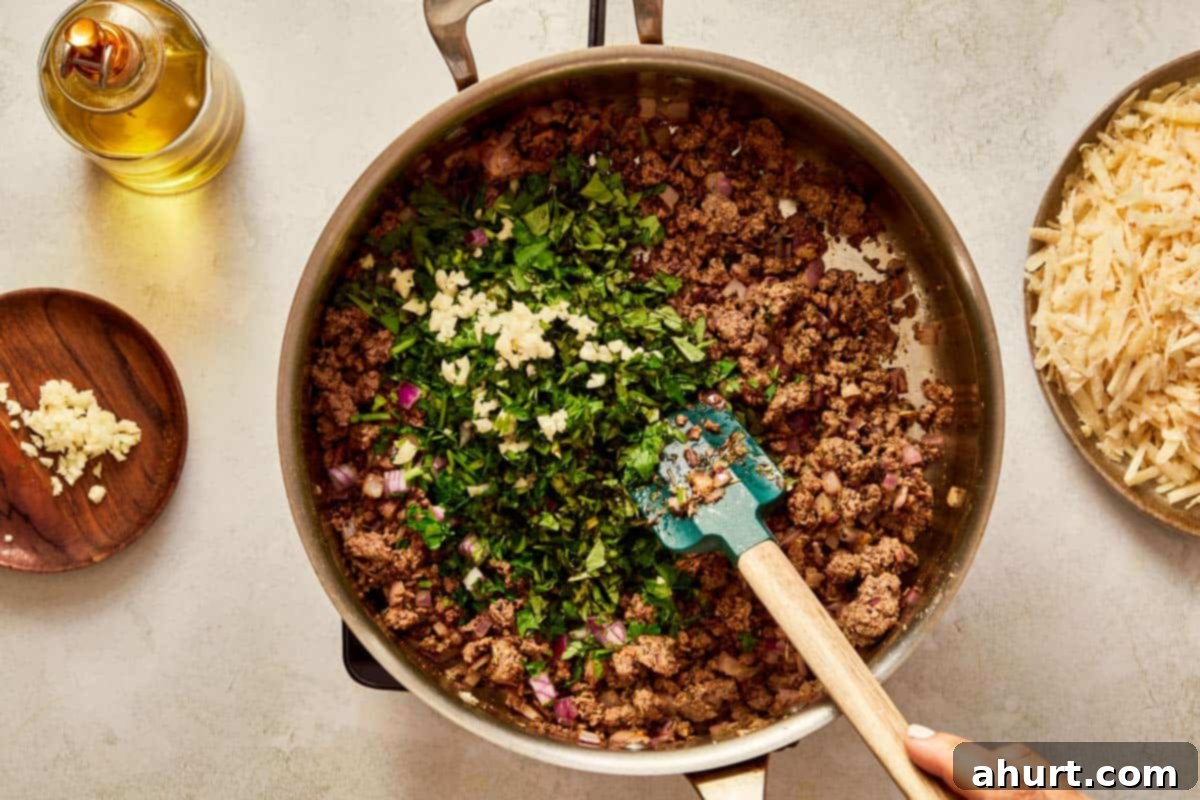 Stirring fresh herbs and garlic into the meat mixture.