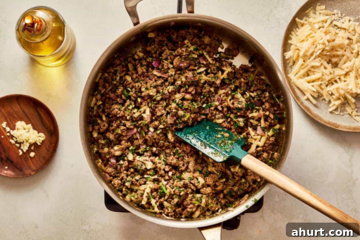 Cooked beef mixed with herbs and Parmesan in a pan.