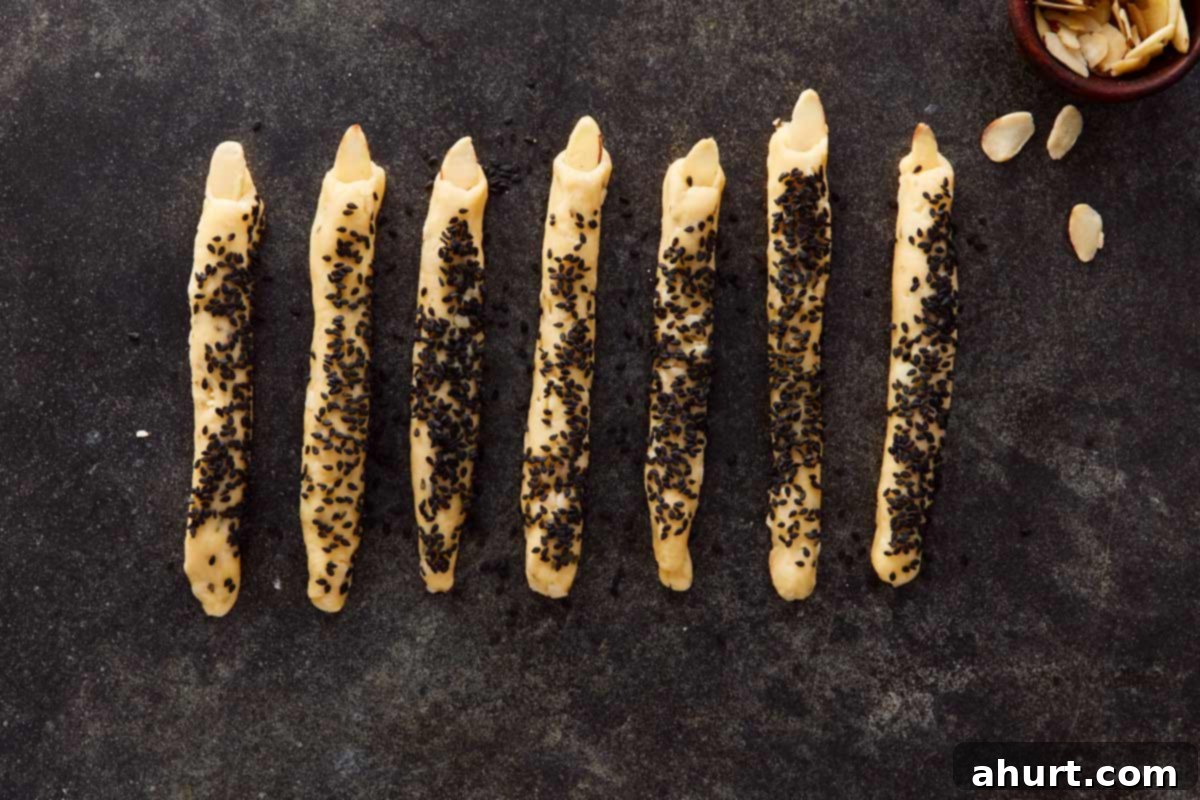 Close-up of shaped fingers topped with almond nails, ready to bake — spooky and detailed.