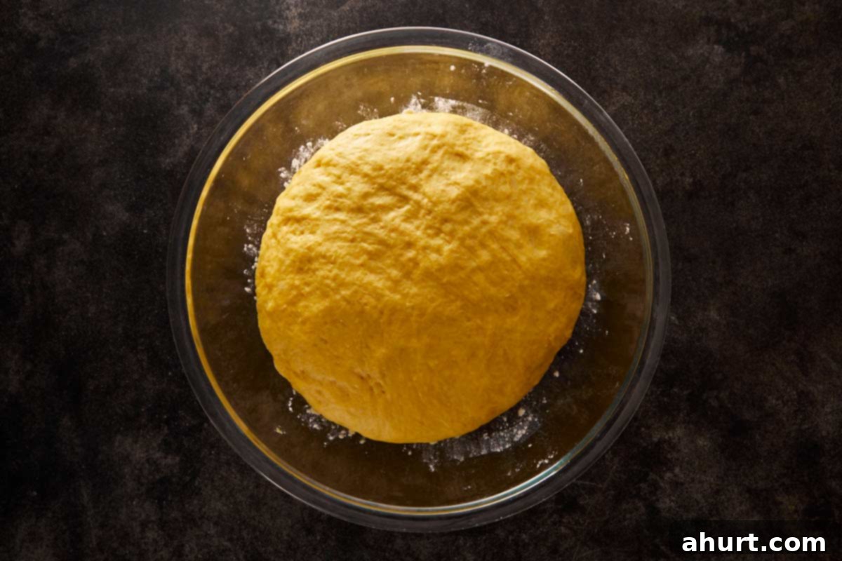Risen pumpkin bread dough in a glass bowl, fluffy and ready to shape.