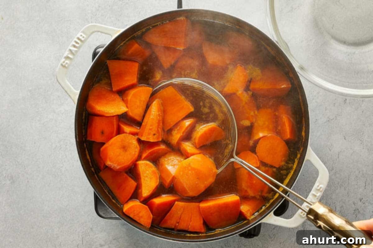 Sweet potato chunks boiling in a large pot of water, with a skimmer lifting pieces out.