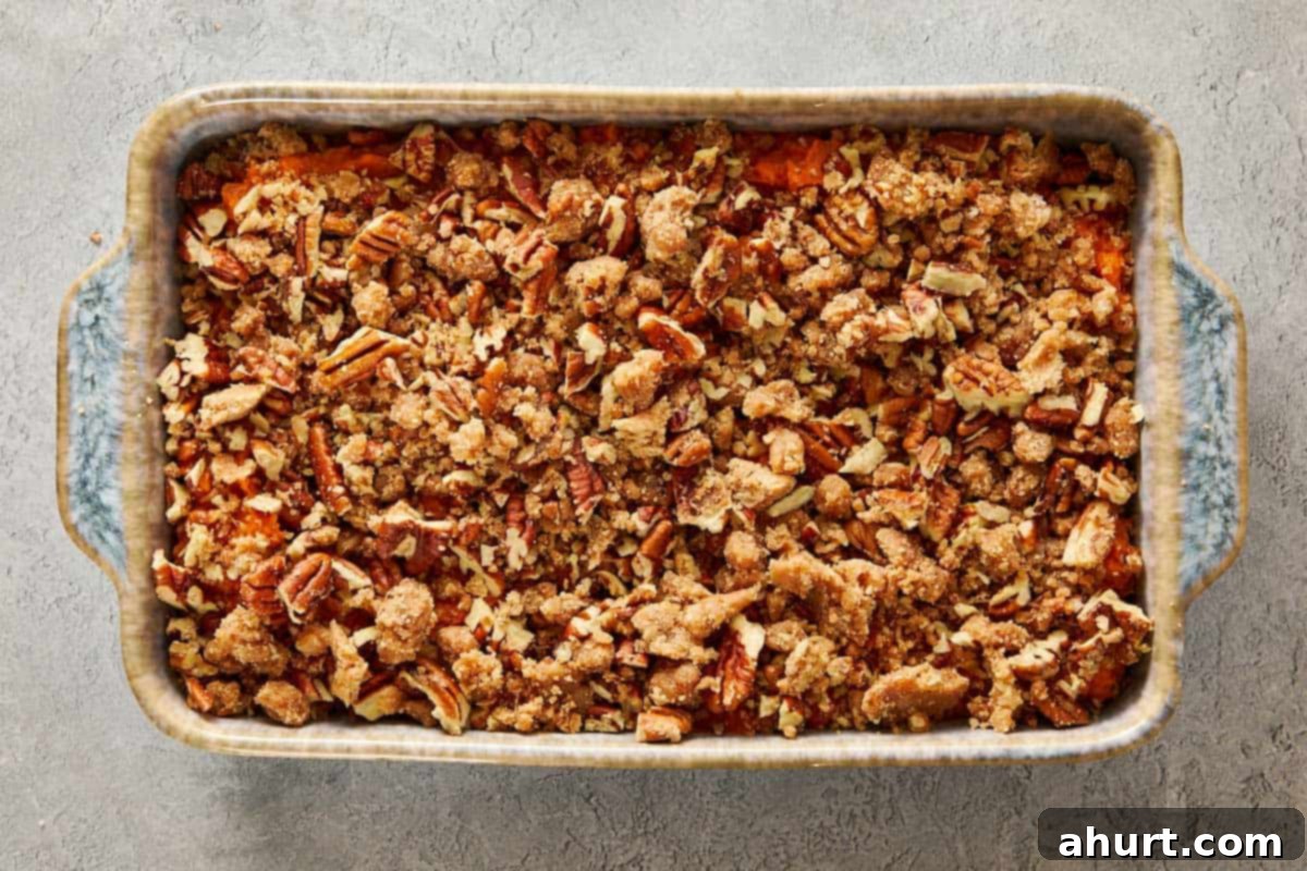 Unbaked sweet potato casserole topped with large white marshmallows spread over a pecan streusel layer