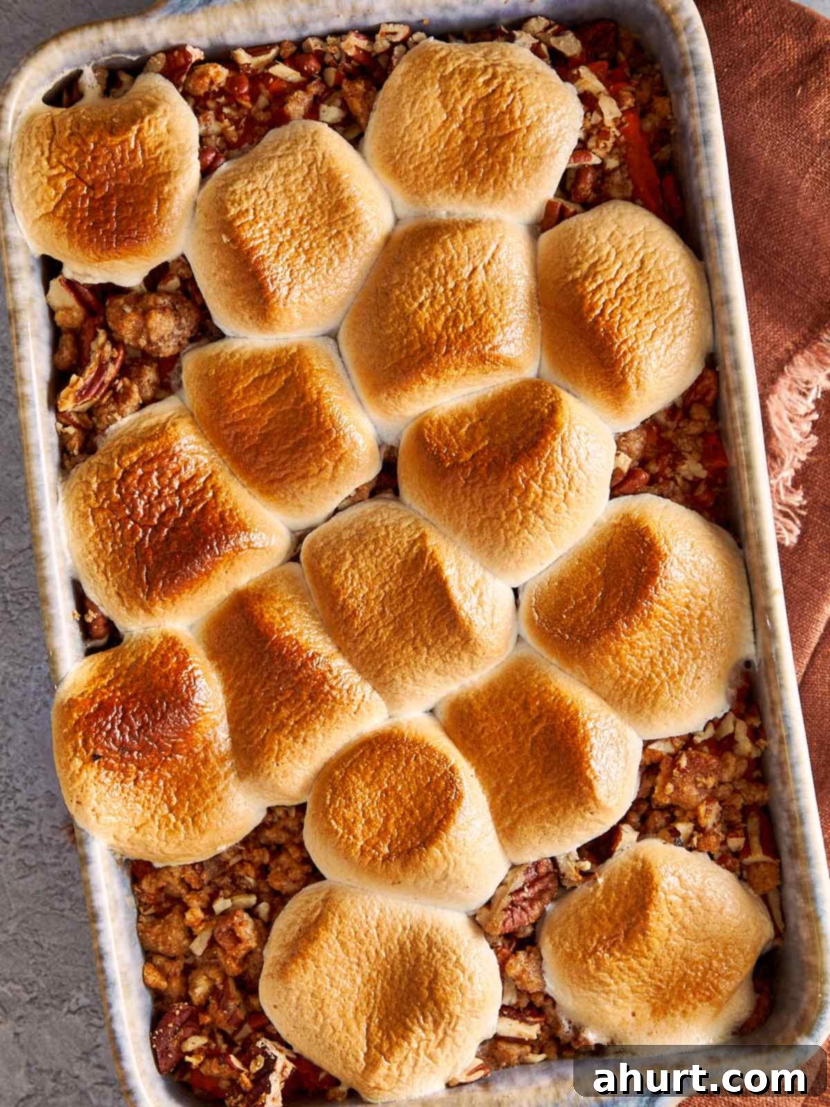 Overhead view of sweet potato casserole with golden toasted marshmallows on top and pecan crumble showing around the edges, fresh from the oven.