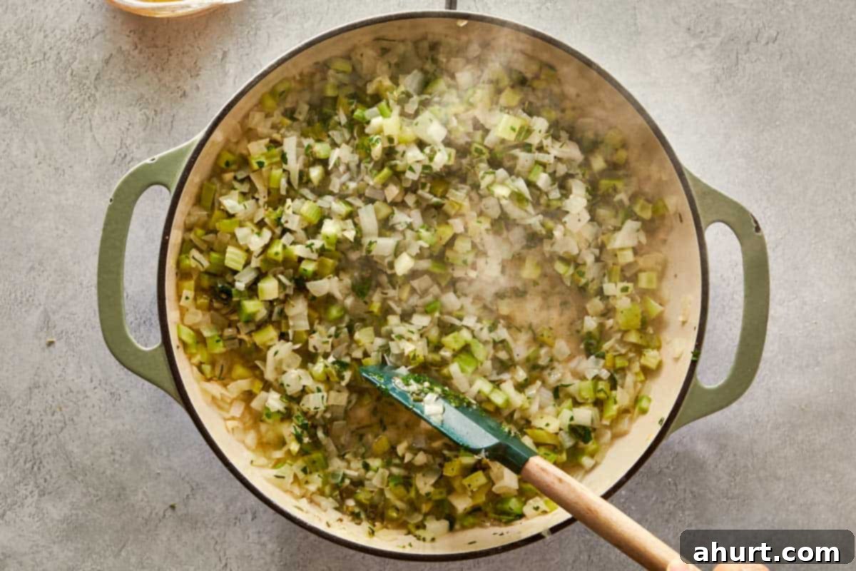 Classic Buttery Herb Stuffing 6 Sautéing chopped onions and celery in a pot with a spatula, with bowls of fresh and dried herbs nearby for stuffing.