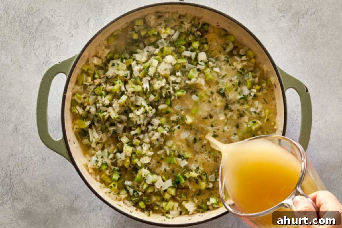 Classic Buttery Herb Stuffing 7 Pouring chicken stock into the pot with sautéed onions, celery, and herbs for moistening stuffing mix.