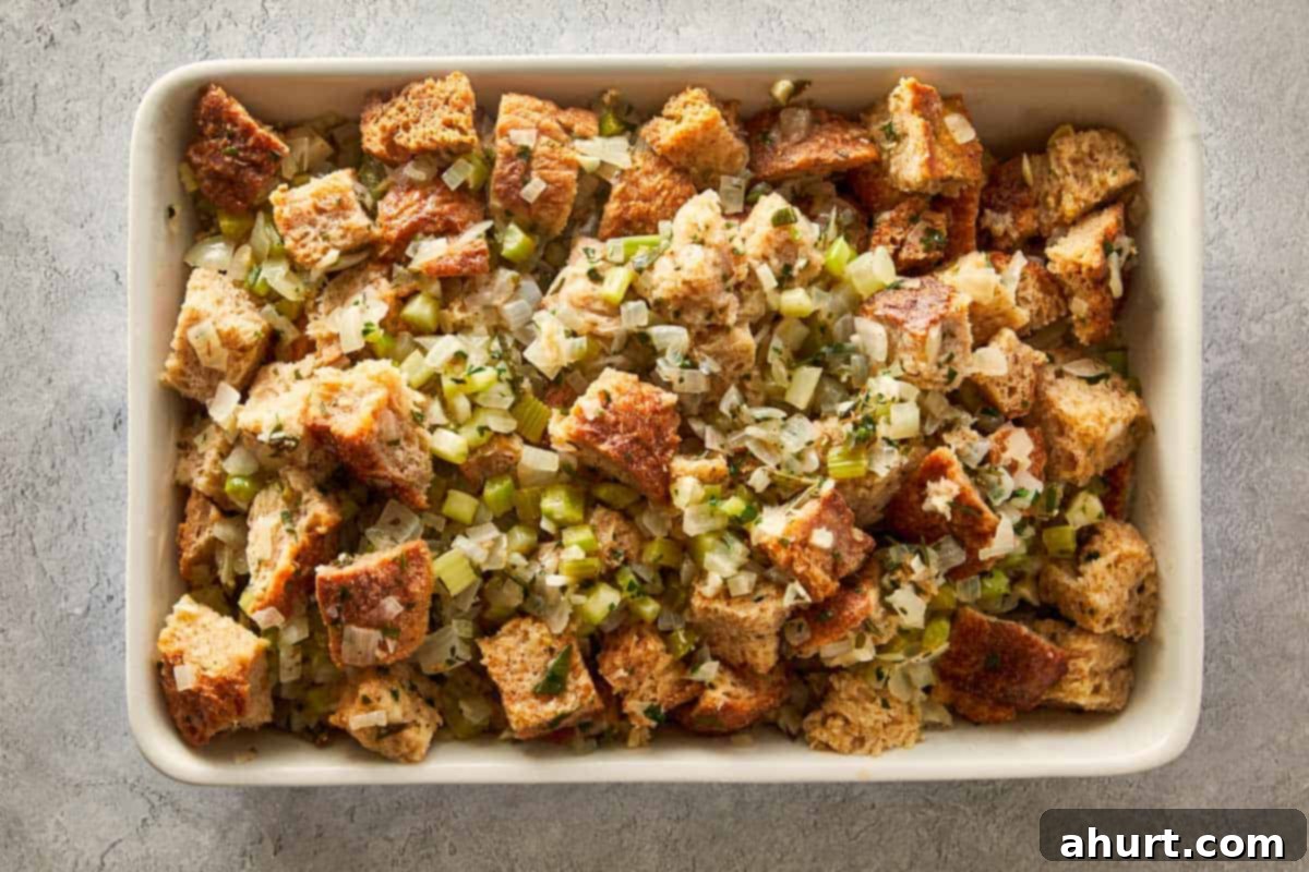 Classic Buttery Herb Stuffing 10 Unbaked stuffing mixture transferred and spread evenly in a white rectangular baking dish before cooking.