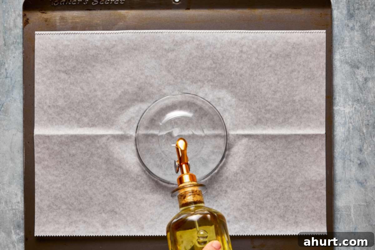 A clear glass bowl, inverted and lightly oiled, placed in the center of a parchment-lined baking tray, ready for arranging dough balls