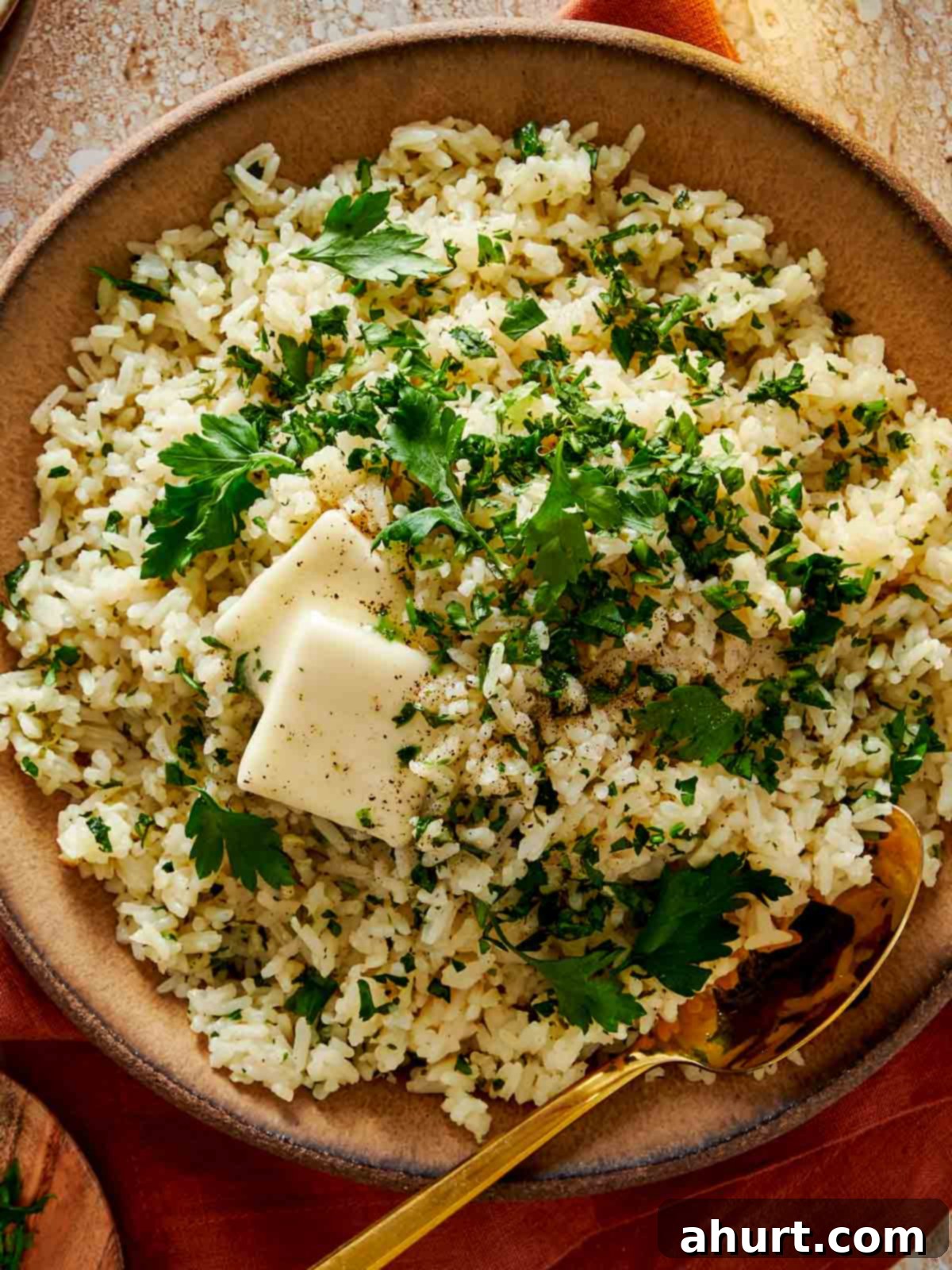 Simple and Flavorful Garlic Butter Rice 12 Close-up, top-down shot of garlic butter rice in a rustic bowl, with a small pat of butter melting on top, garnished with fresh herbs