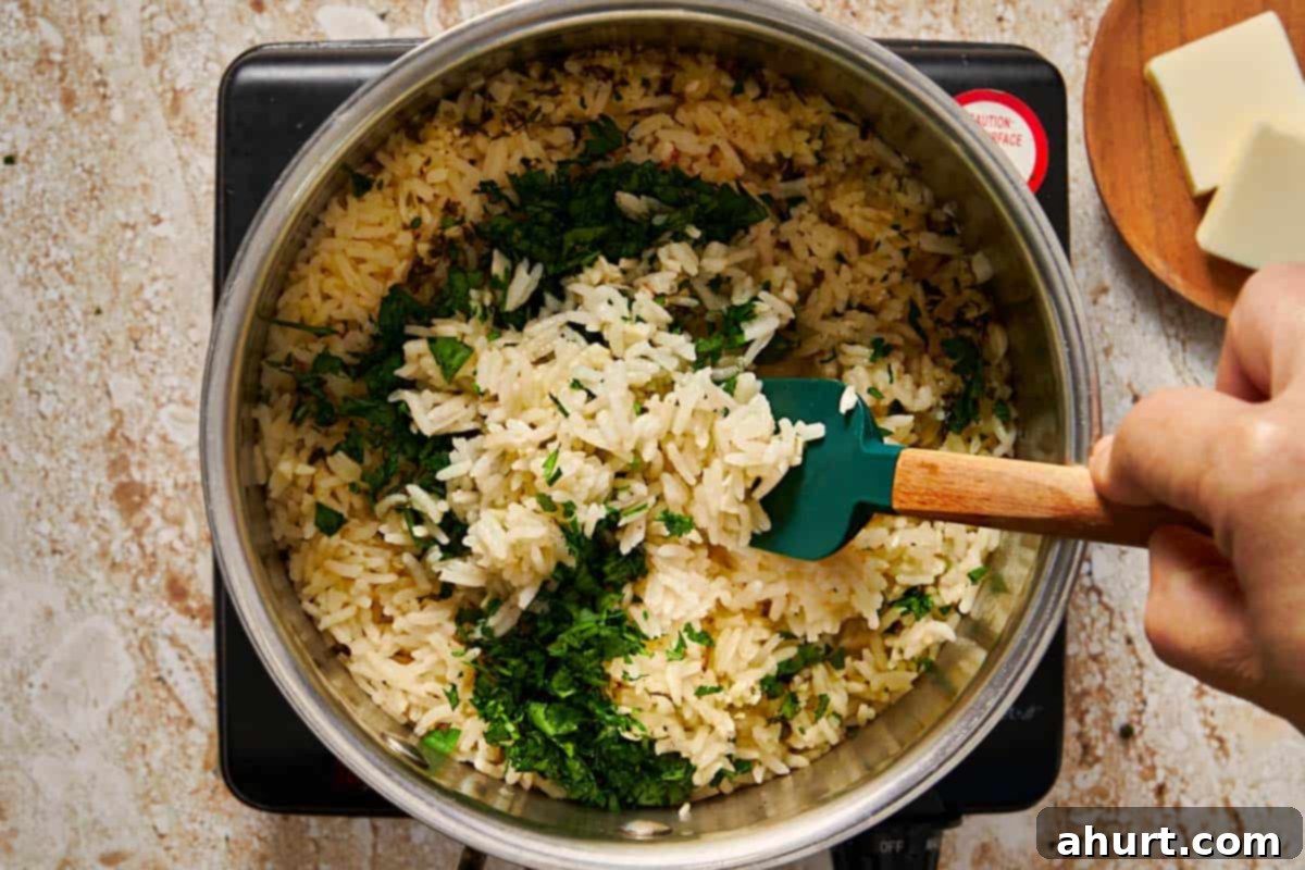 Simple and Flavorful Garlic Butter Rice 8 Fresh chopped parsley being stirred into the perfectly cooked garlic butter rice, adding a fresh finish.
