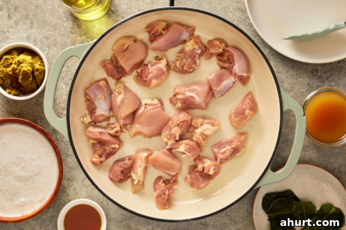 top down shot of a pan with chicken thigh being cooked