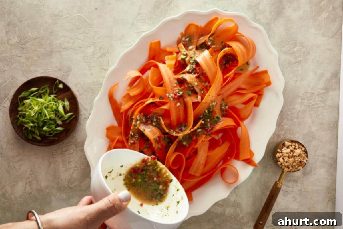 Ginger Peanut Carrot Slaw 7 Carrot ribbons arranged in a bowl, with the freshly prepared Asian dressing being poured generously over them