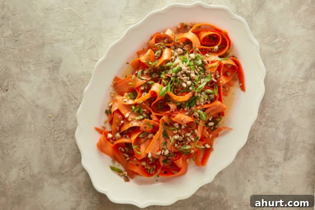 Ginger Peanut Carrot Slaw 8 Finished Asian Carrot Salad served in a stylish bowl, with chopped roasted peanuts and finely chopped green onions being sprinkled on top for garnish