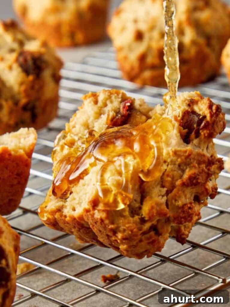 A close up side shot of a muffin on a wire rack cooling with honey being poured over it
