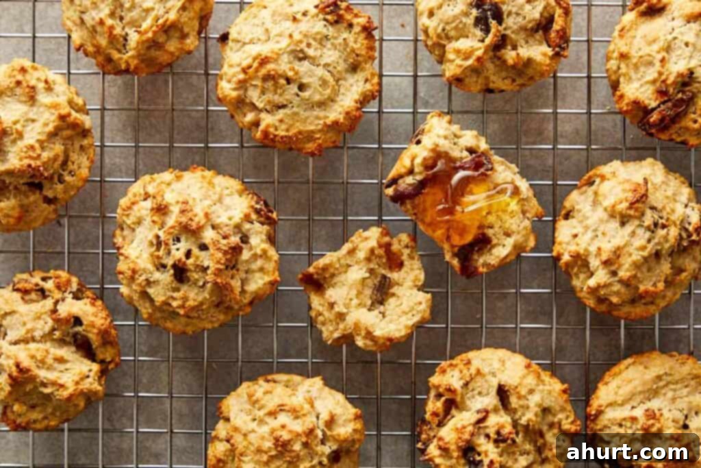 a collection of muffins sitting spaced out on a wire rack cooling with the middle one cut open to show the insides