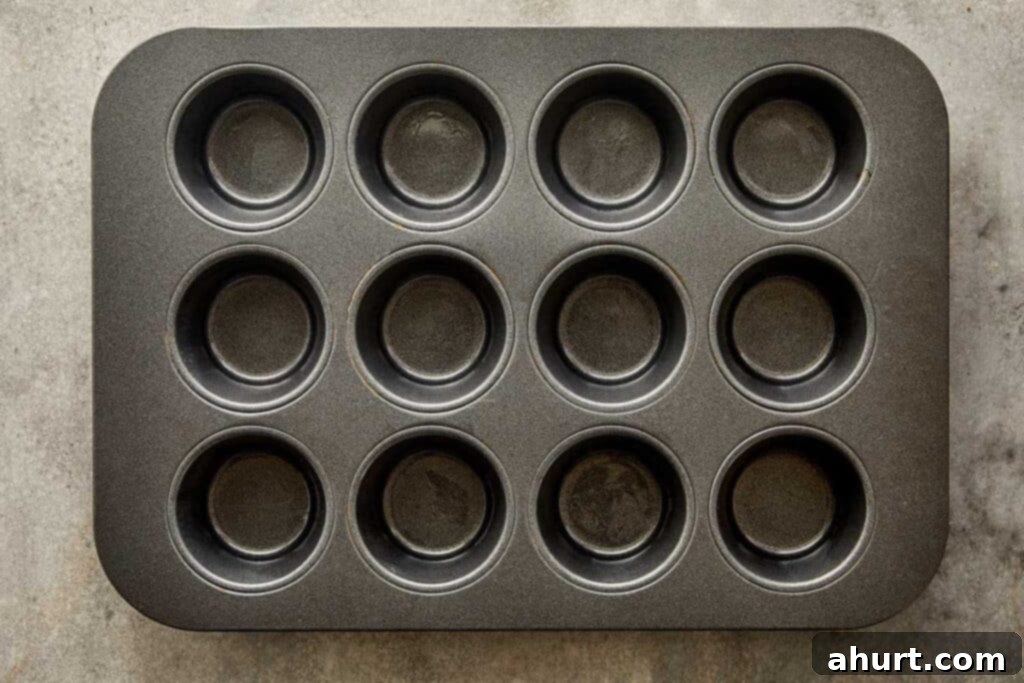 A top down view of a muffin tray non stick dark grey with 12 holes