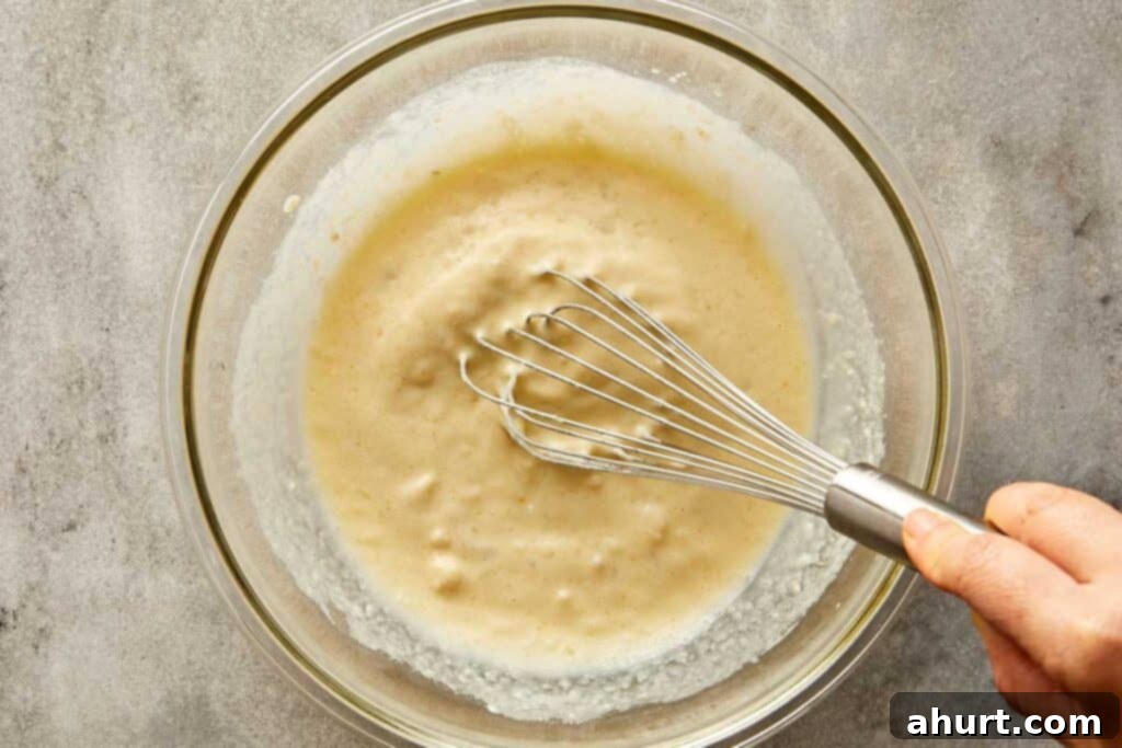 a top down shot of a mixing bowl with a whisk mixing the batter