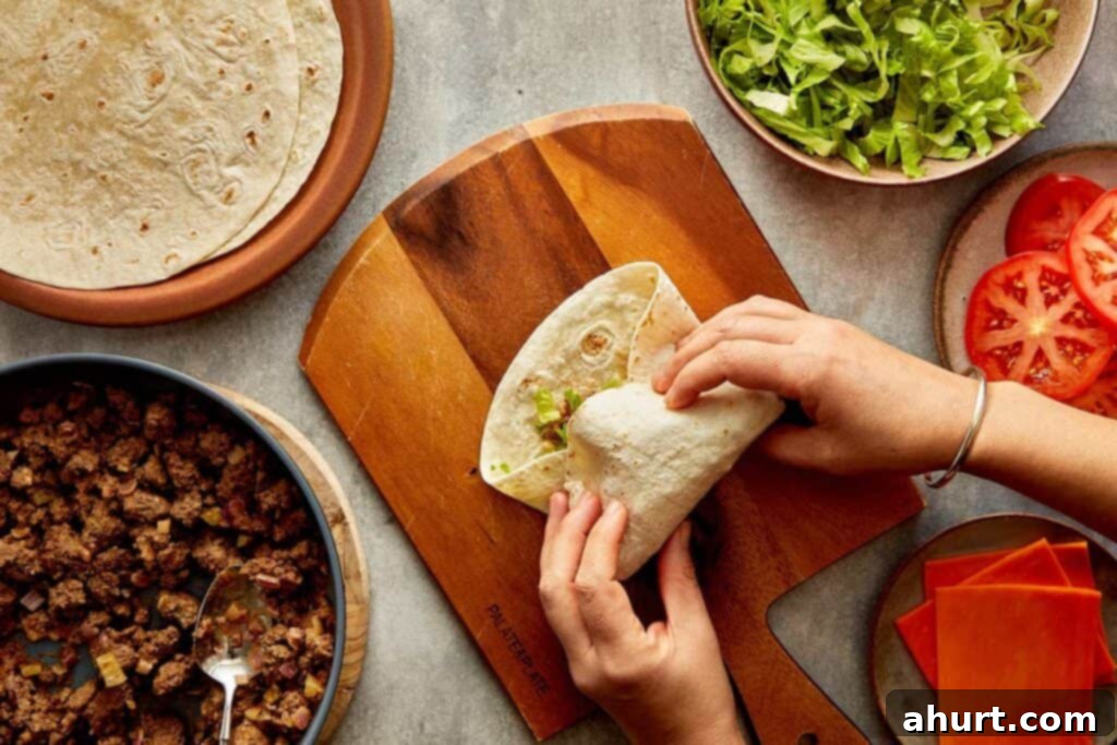 Cheeseburger Bliss Wrap 15 Tortilla wrap with lettuce and mince being folded by female hands.