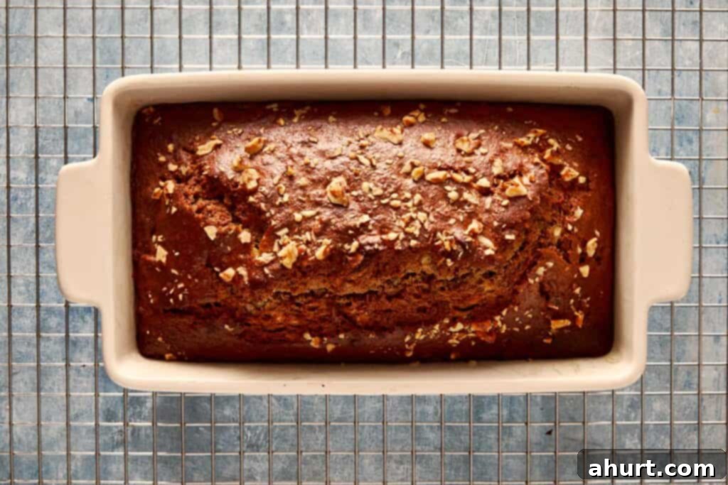 A top-down view of the baked banana bread in a rectangular loaf pan, resting on a wire cooling rack.